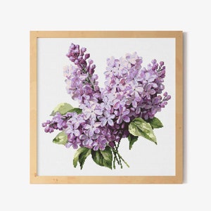 May include: A framed cross-stitch embroidery of a bouquet of purple lilac flowers with green leaves.