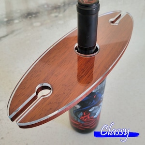 May include: A wooden wine bottle holder with a cutout design. The holder is brown with a light wood grain and has a silver trim. The holder is designed to hold a bottle of wine upright. The word "Classy" is printed in blue on the bottom of the image.