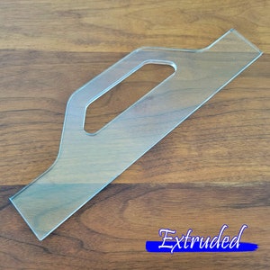 May include: A clear plastic template with a handle, labeled "Extruded". This template is used for creating custom shapes and designs.