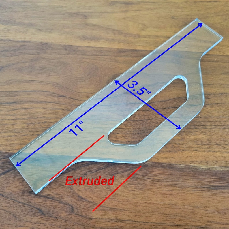 May include: A clear plastic template for making an extruded shape, measuring 11 inches long and 3.5 inches wide. The template has a cutout in the shape of a handle.