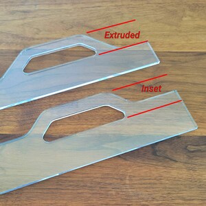 May include: Two clear plastic rulers with handles. The top ruler has the word "Extruded" written on it. The bottom ruler has the word "Inset" written on it.