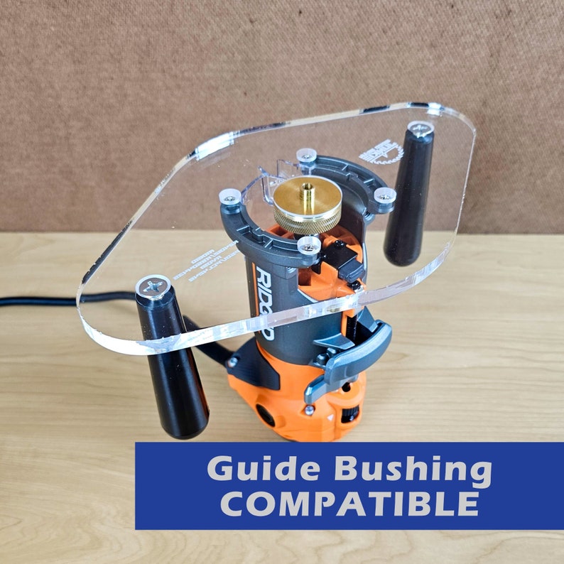 Pu&ograve; includere: Un modello di fresatura in acrilico trasparente con un router nero e arancione attaccato. Il modello ha tre gambe nere e una boccola di guida in ottone. Il testo "GUIDE BUSHING COMPATIBLE" &egrave; stampato in blu su sfondo bianco.