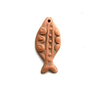 May include: A terracotta fish pendant with a decorative design. The fish is brown and has a hole at the top for hanging.