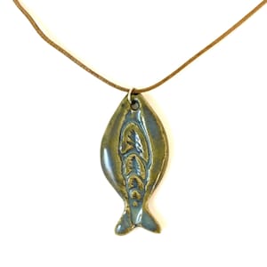 May include: A ceramic fish pendant necklace with a brown leather cord. The fish is green and blue with a detailed design.