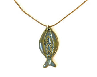 May include: A ceramic fish pendant necklace with a brown leather cord. The fish is green and blue with a detailed design.