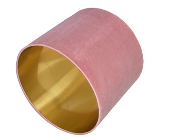 May include: A pink velvet lampshade with a gold interior. The lampshade is cylindrical in shape.