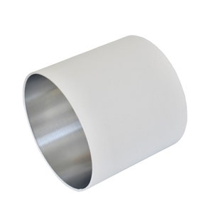 May include: A white cylindrical lampshade with a silver metal lining. The lampshade is made of a textured fabric.