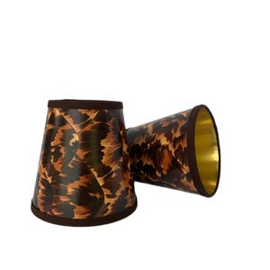 May include: Two brown and gold lampshades with a leopard print pattern.