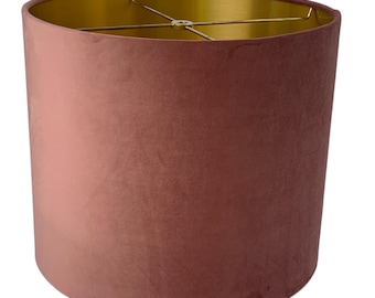 May include: A dusty rose velvet lampshade with a gold interior. The lampshade is cylindrical in shape and has a smooth, soft texture.
