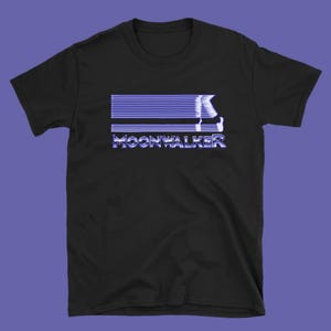 May include: Black t-shirt featuring a blue and white graphic design. The design includes horizontal lines and the word "MOONWALKER" in a stylized font. The graphic also depicts a figure in motion.