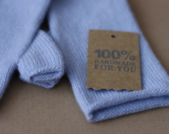 May include: A pair of light blue knitted fingerless gloves with a brown tag that reads "100% Handmade For You".