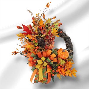 May include: A fall-themed wreath with a grapevine base, adorned with colorful autumn leaves, berries, and a small pumpkin. The wreath features a large bow with orange, green, and yellow ribbons, creating a festive and seasonal decoration.
