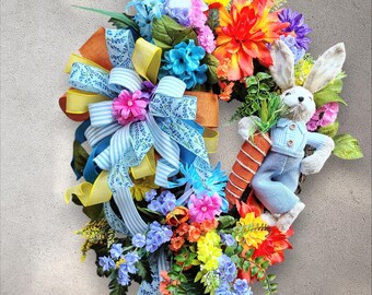 Cute Sisal Bunny Hangs Out with His Huge Carrot Among the Pastel Florals on this Grapevine Wreath with Multi, Bright Blue, Designer Bow
