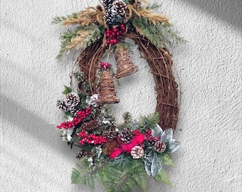 May include: A festive Christmas wreath made of woven twigs, adorned with pinecones, red berries, and faux greenery. Two small woven bells hang in the center. The wreath is decorated with a red bow and frosted accents.