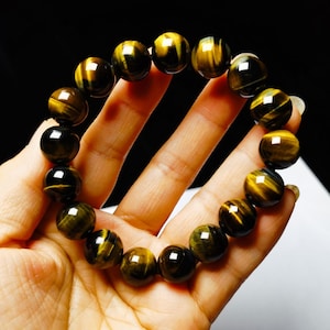 Könnte beinhalten: Ein Armband aus runden, braunen und goldenen Tigeraugenperlen.