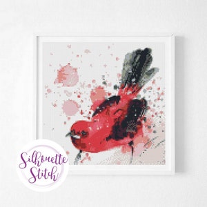 May include: A red bird with black wings and a white background with pink watercolor splatters.