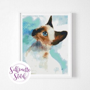 May include: A close-up of a white and brown cat with blue eyes looking up. The cat is against a blue and white watercolor background.
