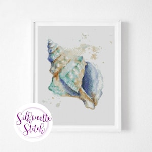 May include: A cross stitch pattern of a seashell with a blue, green, and brown color scheme. The shell is on a white background with a few scattered brown dots.