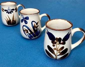 Vintage Stoneware Set Of Three 12 Ounce Mugs, Adorned With Hand Painted Indigo Blue Flowers with Brown Leaves, Handles, and Rims.