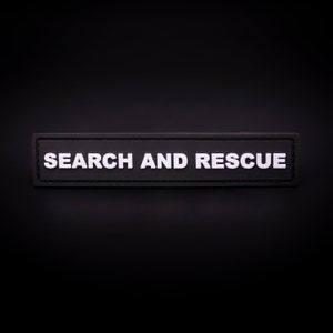 May include: Black patch with white stitching and the text "SEARCH AND RESCUE" in white.