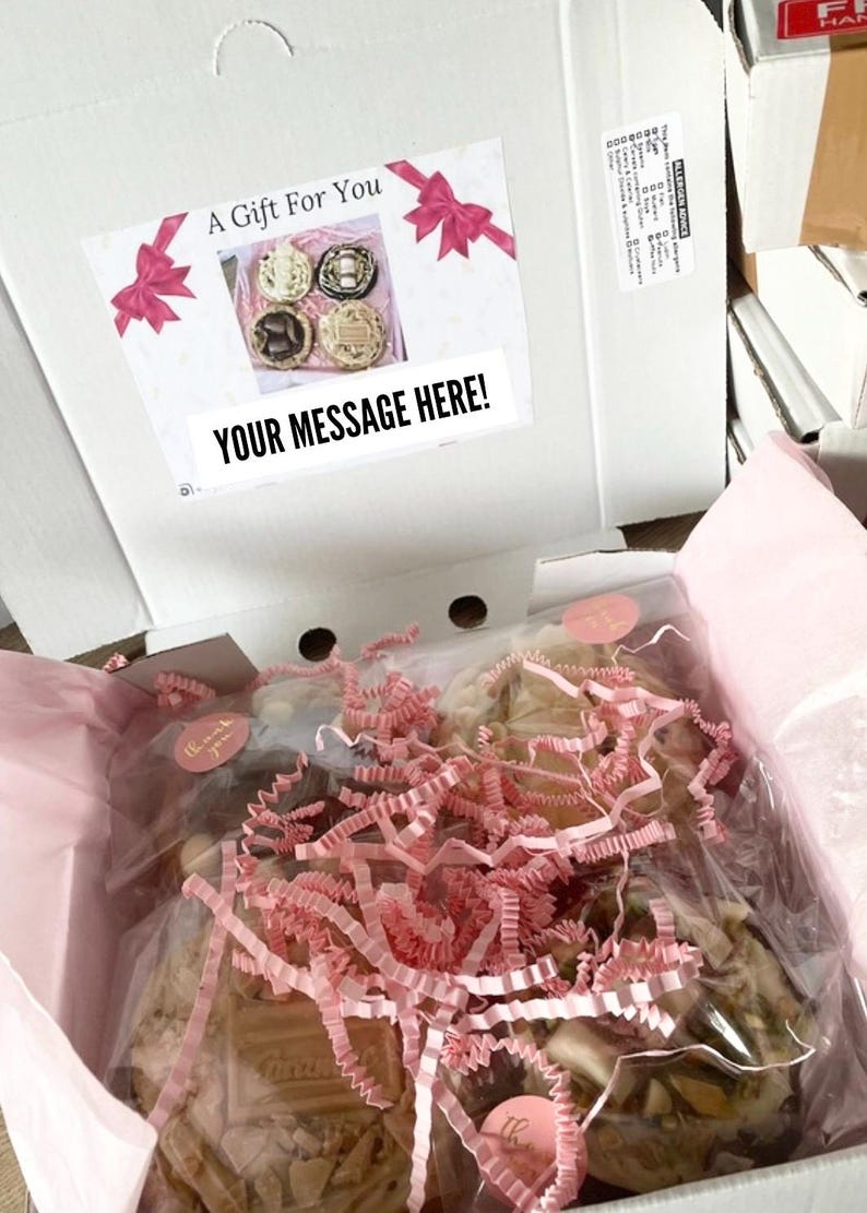 May include: A white cardboard gift box containing individually wrapped round cookies nestled in pink shredded paper. The inside lid features a label with pink bows, the text A Gift For You, a small photo of four cookies, and the text YOUR MESSAGE HERE.