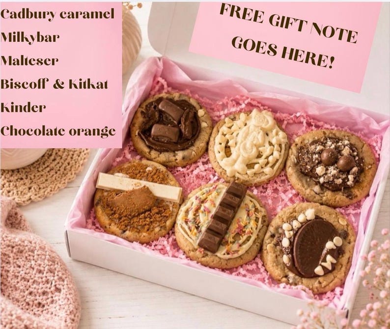 May include: A white gift box containing six assorted cookies topped with various chocolate candies. The box includes pink tissue paper and a sign that reads FREE GIFT NOTE GOES HERE! The text lists Cadbury caramel, Milkybar, Malteser, Biscoff & Kitkat, Kinder, and Chocolate orange.