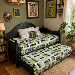 May include: A black daybed with a pull-out trundle, both covered with a quilt featuring a patchwork design in shades of green, black, and white. The room has olive green walls, a jute rug, and decorative artwork.