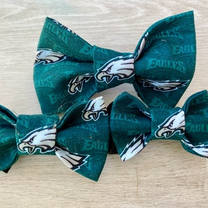 May include: Three green bow ties with a white Philadelphia Eagles logo and the word "Eagles" printed on them.
