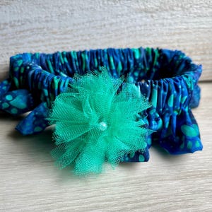 May include: A blue and green patterned garter with a green tulle flower.