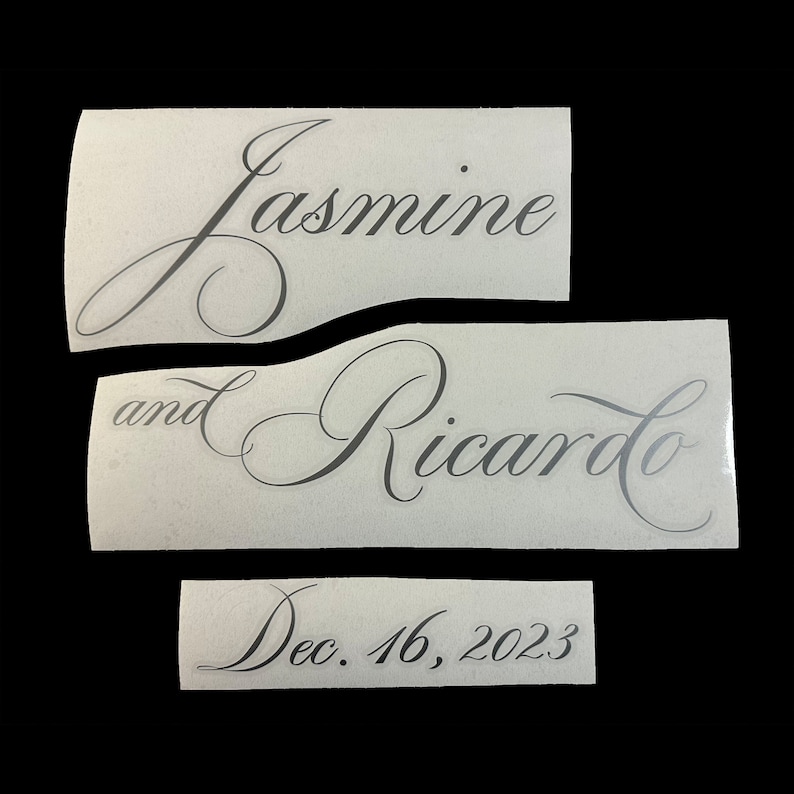 May include: Three white pieces of paper with black calligraphy text. The top piece says "Jasmine", the middle piece says "and Ricardo", and the bottom piece says "Dec. 16, 2023".