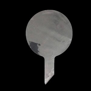 Puede incluir: Un adorno para pastel de pl&aacute;stico transparente con una parte superior redonda y plana y una parte inferior puntiaguda.