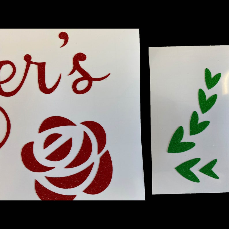 Peut inclure: Deux autocollants en vinyle, l'un avec le mot "er's" en lettres cursives rouges et une rose rouge paillet&eacute;e, et l'autre avec une branche feuillue paillet&eacute;e verte.