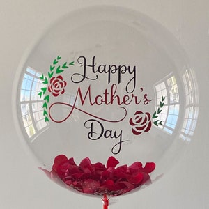 Peut inclure: Ballon transparent rempli de p&eacute;tales de roses rouges et un message qui dit "Joyeuse f&ecirc;te des m&egrave;res" avec des feuilles vertes et des roses rouges.