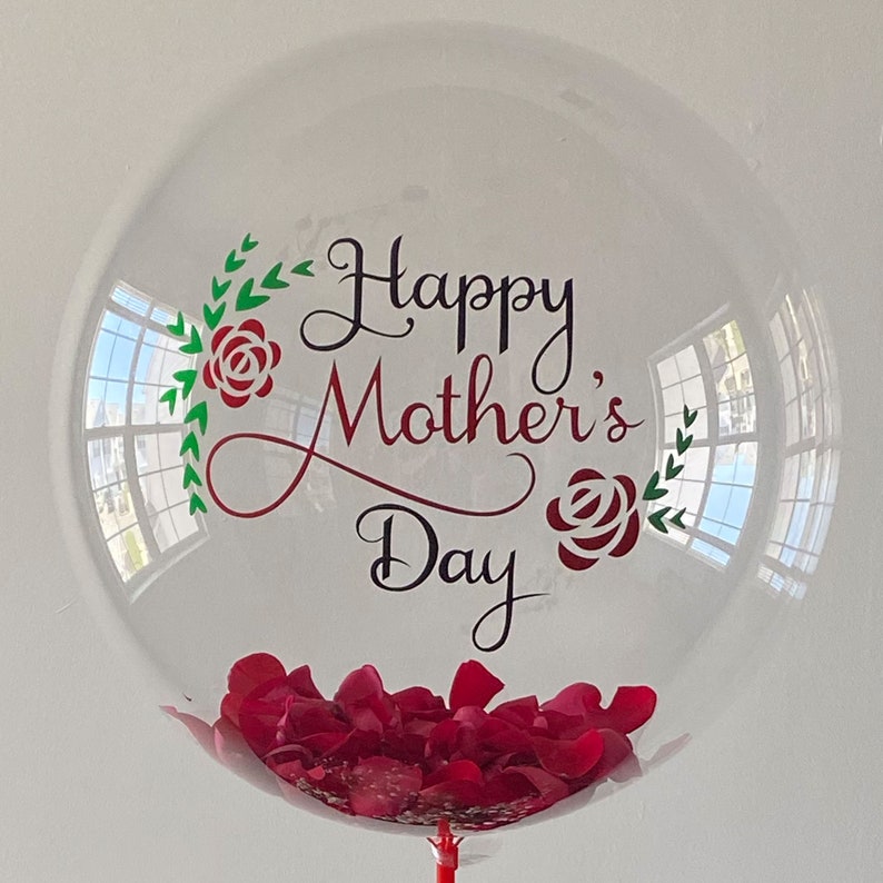 Peut inclure: Ballon transparent rempli de p&eacute;tales de roses rouges et un message qui dit "Joyeuse f&ecirc;te des m&egrave;res" avec des feuilles vertes et des roses rouges.
