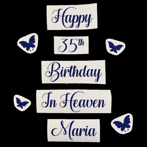 May include: A collection of white paper cutouts with dark blue text and butterfly accents. The text reads "Happy 35th Birthday In Heaven Maria". The cutouts are arranged on a black background.