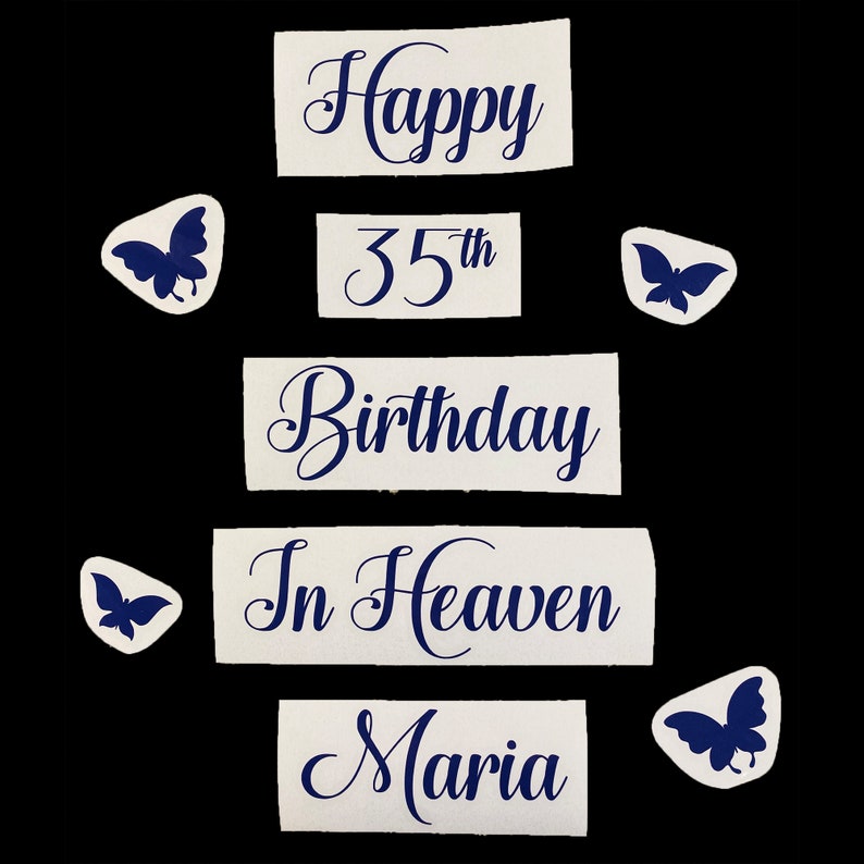 May include: A collection of white paper cutouts with dark blue text and butterfly accents. The text reads "Happy 35th Birthday In Heaven Maria". The cutouts are arranged on a black background.
