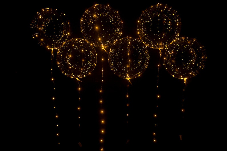 Puede incluir: Un conjunto de seis globos transparentes con luces LED blancas c&aacute;lidas en su interior. Los globos est&aacute;n ensartados juntos con las luces colgando.