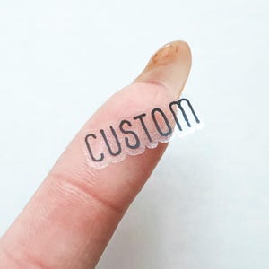 May include: A clear sticker with the word "CUSTOM" printed in black.