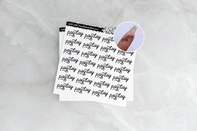 May include: A sheet of white sticker paper with the word "payday" written in cursive multiple times. The stickers are designed for use in a planner or journal.