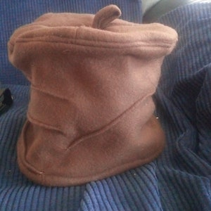 May include: A brown felt bucket hat with a pointed top. The hat is folded down and has a seam running down the side.