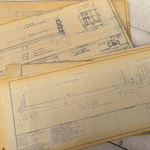 May include: Close-up of a set of vintage blueprints for a 70-ton flat bed trailer for gypsum loading. The blueprints are labeled "C80" and show the dimensions of the trailer in inches.