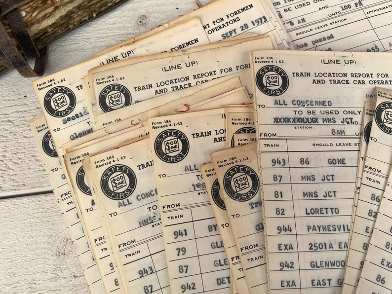 May include: A stack of vintage train safety forms with the text "Safety First" and a dollar sign logo. The forms are printed on white paper and have black ink. The forms are dated September 28, 1973.