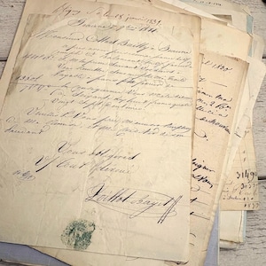Könnte beinhalten: Ein Stapel antiker, cremefarbener Papierdokumente mit handschriftlichem französischem Kursivtext in schwarzer Tinte. Die Papiere zeigen Altersspuren mit Vergilbung, Knicken und einem kreisförmigen grünen Stempel auf dem unteren linken Blatt.