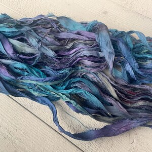 K&ouml;nnte beinhalten: Ein B&uuml;ndel aus t&uuml;rkisfarbenem, blauem und violettem Seidenband. Das Band ist ausgefranst und hat einen rustikalen, Vintage-Look.