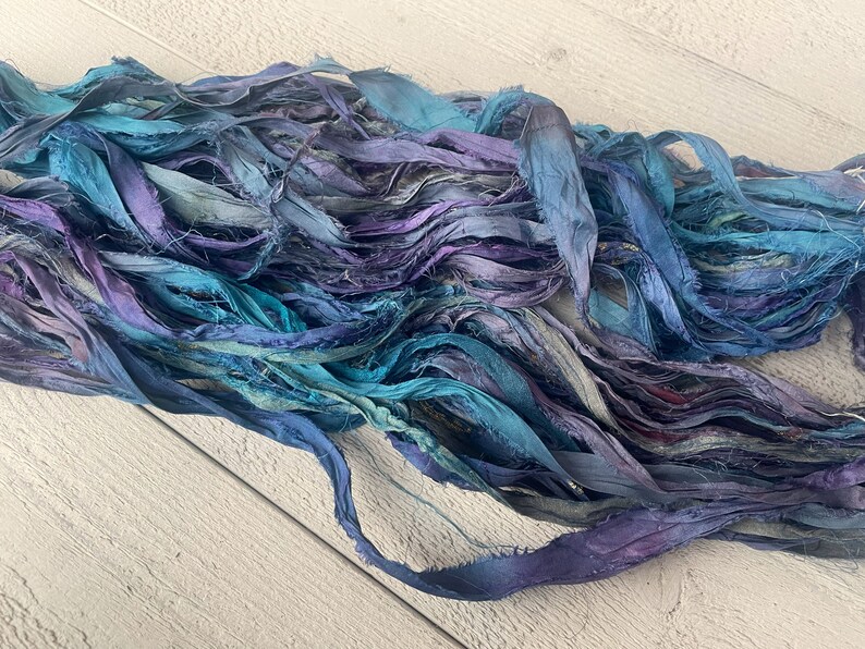 K&ouml;nnte beinhalten: Ein B&uuml;ndel aus t&uuml;rkisfarbenem, blauem und violettem Seidenband. Das Band ist ausgefranst und hat einen rustikalen, Vintage-Look.