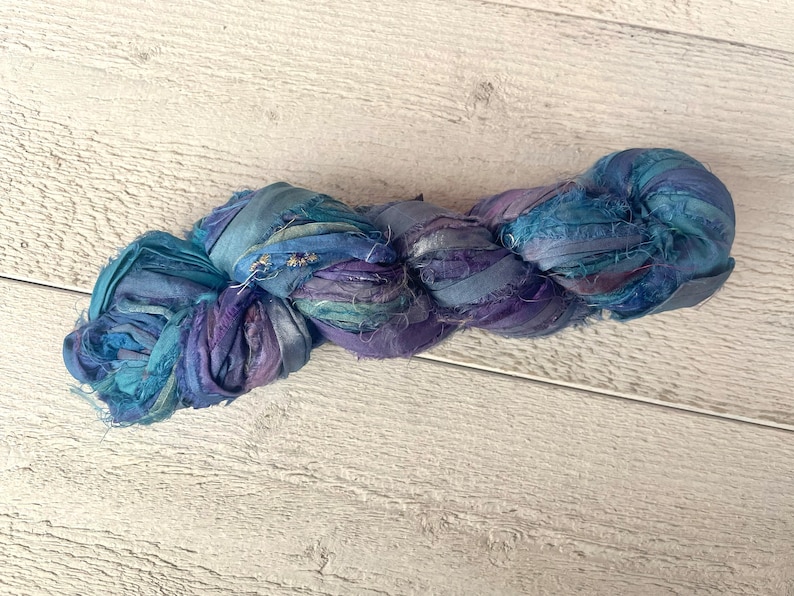 K&ouml;nnte beinhalten: Ein Kn&auml;uel aus blauem und violettem Seidenband, perfekt zum Basteln oder um Ihren Projekten einen Hauch von Eleganz zu verleihen.