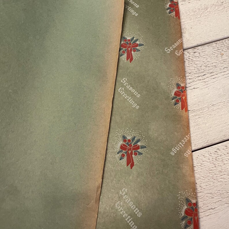 May include: A sheet of green wrapping paper with a white and red pattern of holly and bows. The paper has the text "Seasons Greetings" repeated throughout.