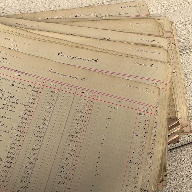 May include: A stack of vintage ledger pages with handwritten entries. The pages are yellowed with age and have red lines separating the columns. The text on the pages includes "Pennsylvania R.R." and "Account No. 2".