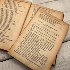 Könnte beinhalten: Eine Nahaufnahme einer Seite aus einem alten Buch mit dem Titel "Der Widerspenstigen Zähmung" von William Shakespeare. Der Text ist in Schwarzweiß und die Seite ist gealtert und vergilbt. Der Text enthält die Nummer der Szene und des Akts sowie die Namen der Figuren.