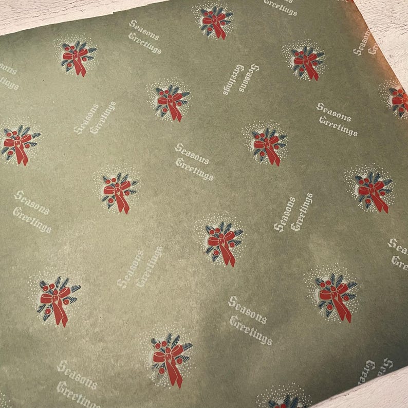 May include: Green wrapping paper with a repeating pattern of red and green wreaths and the text "Seasons Greetings".